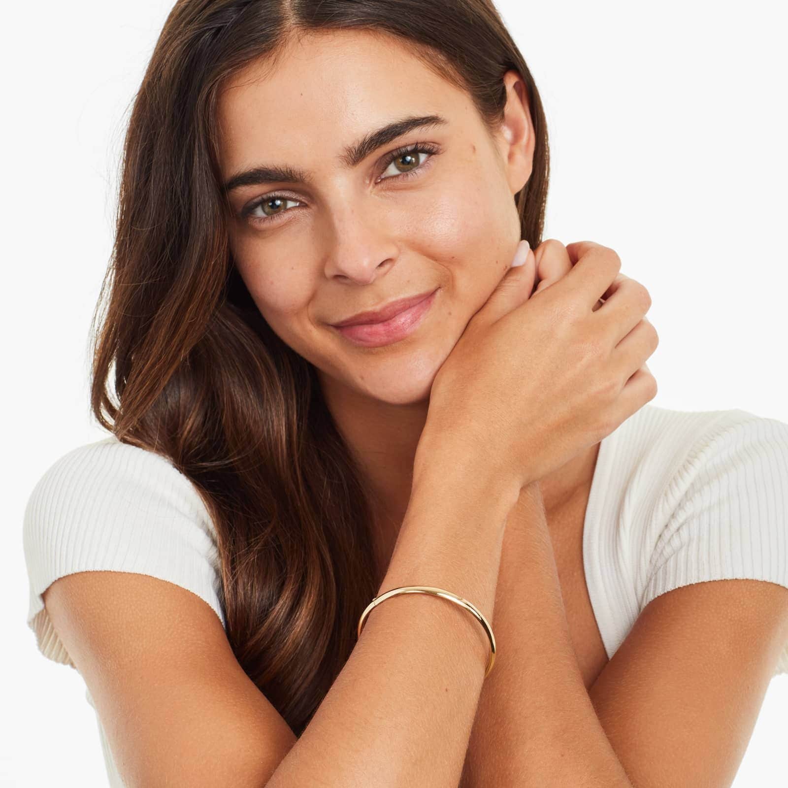 14k yellow gold polished bangle bracelet on the woman's wrist