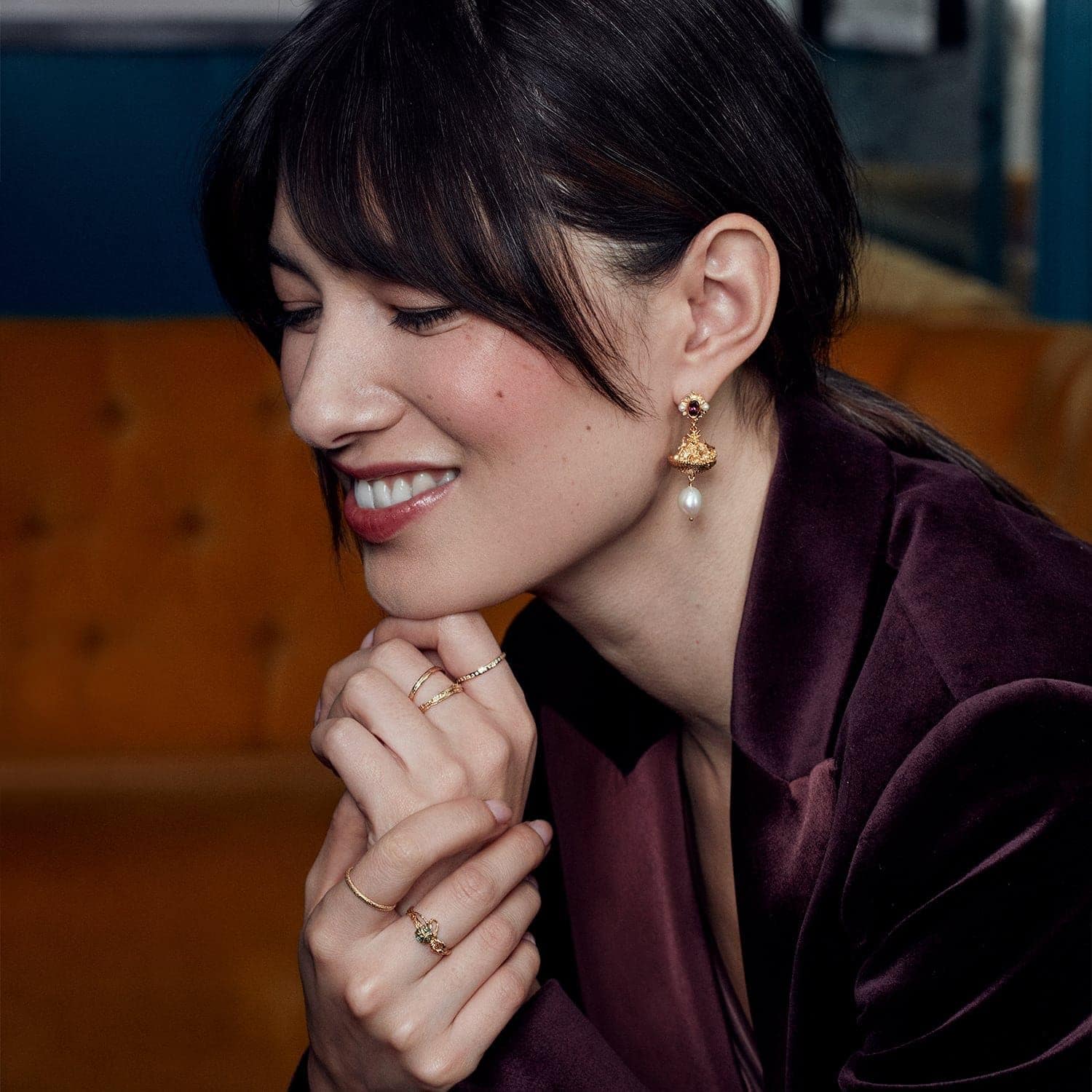 a woman wearing gold earrings and rings