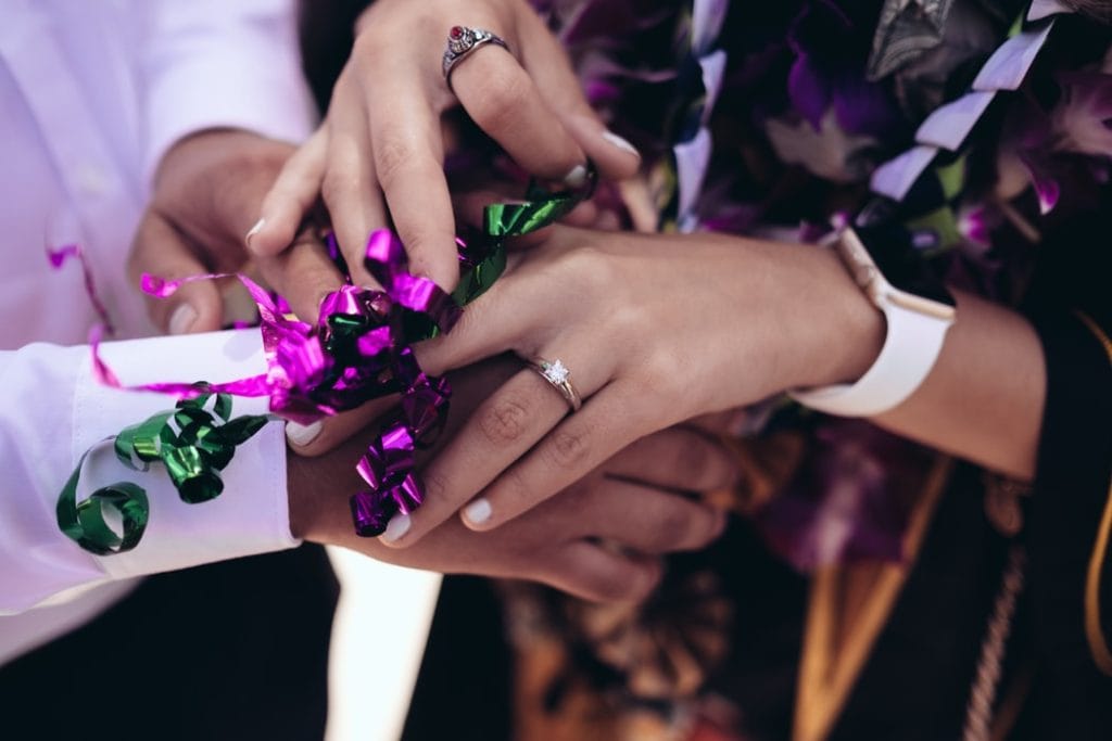 Bride wearing princess cut engagement ring holding groom's hand