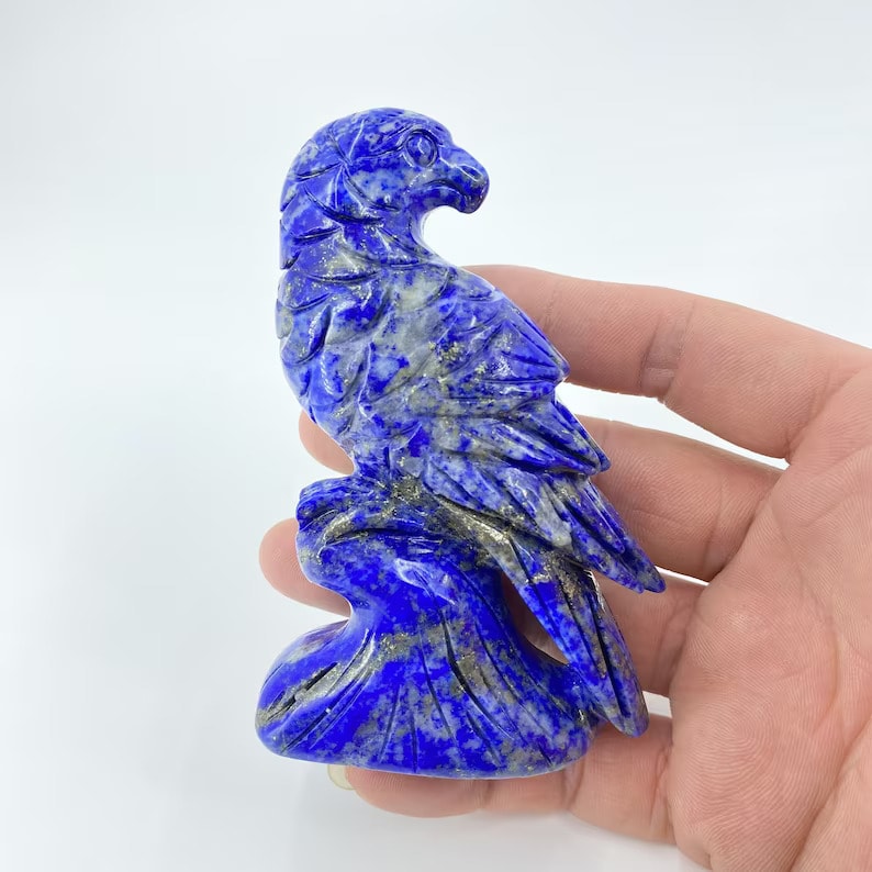 a hand golding lapis lazuli eagle stand