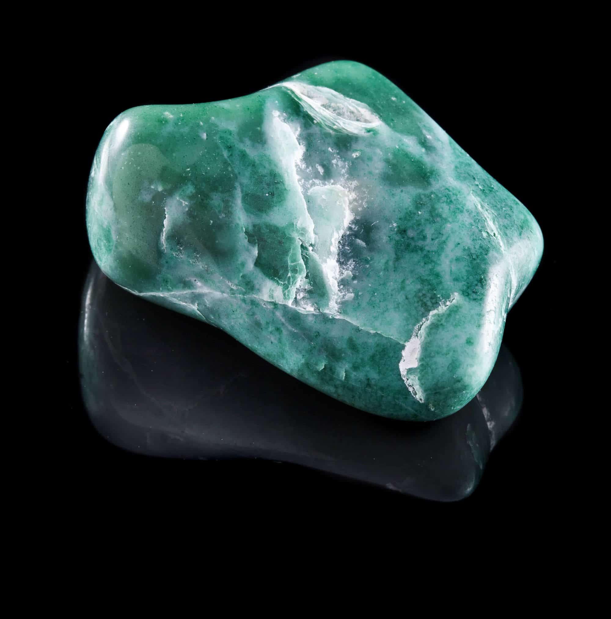Jadeite mineral stone close up with reflection on black surface background