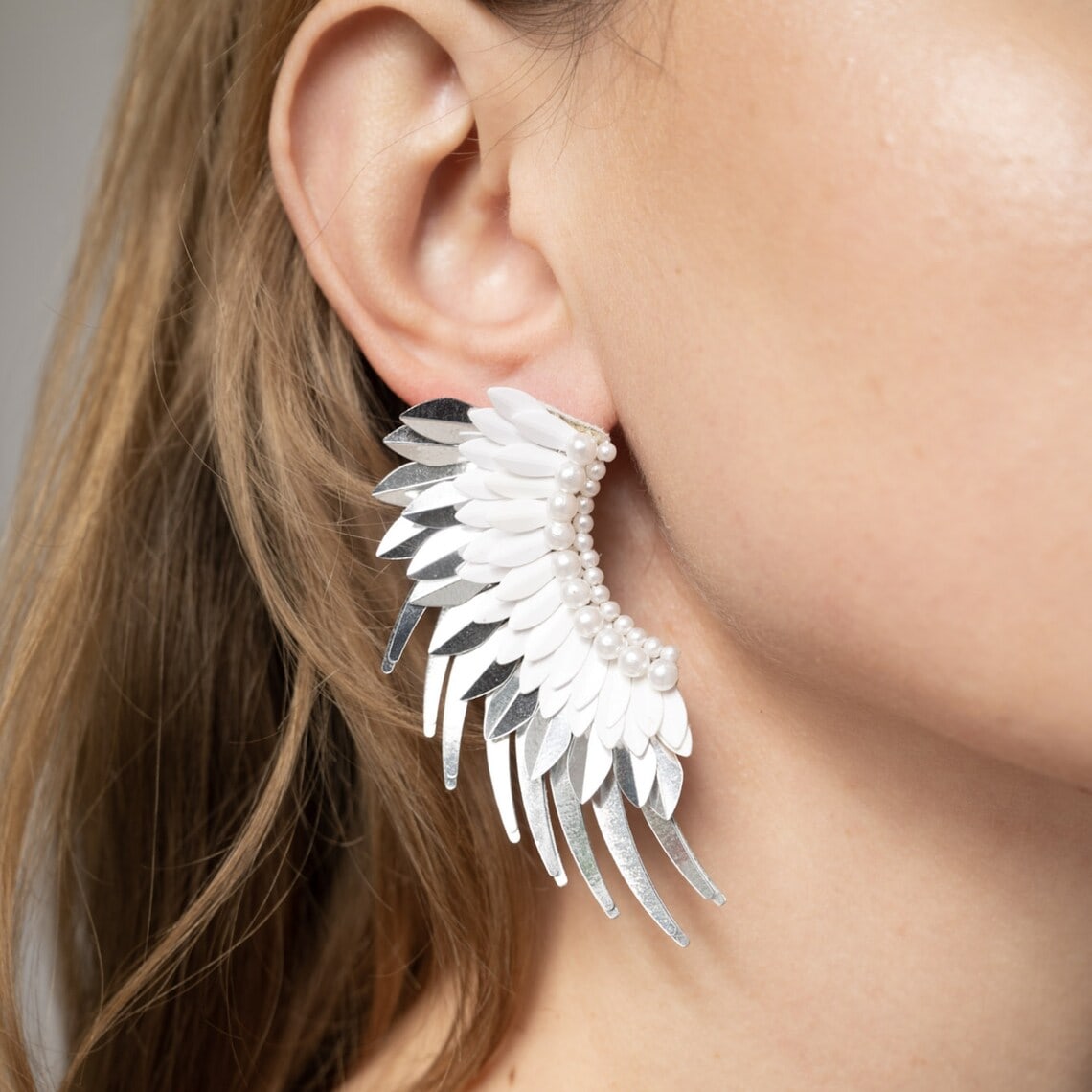 large wing earrings on the ear