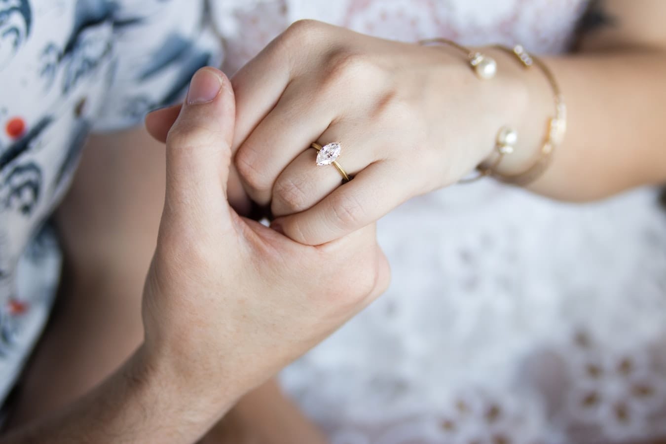 mans hand holding girls hand with marquise cut ring