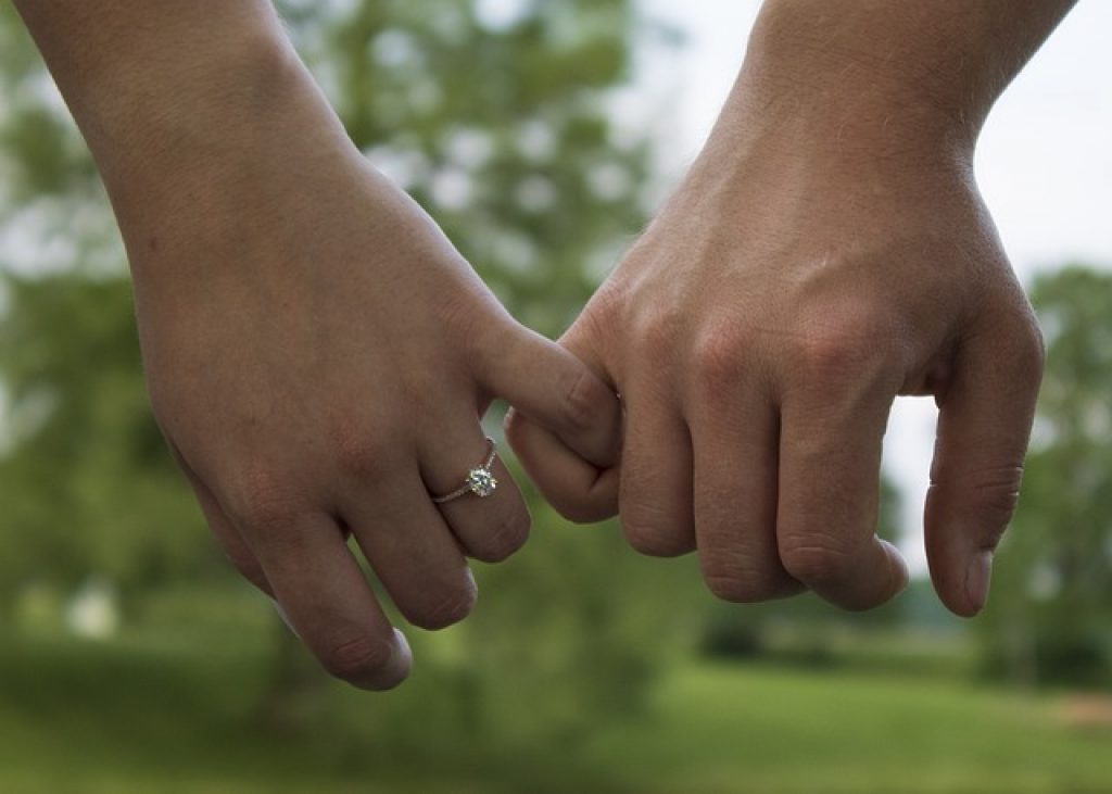 two hands interlocked with diamond ring