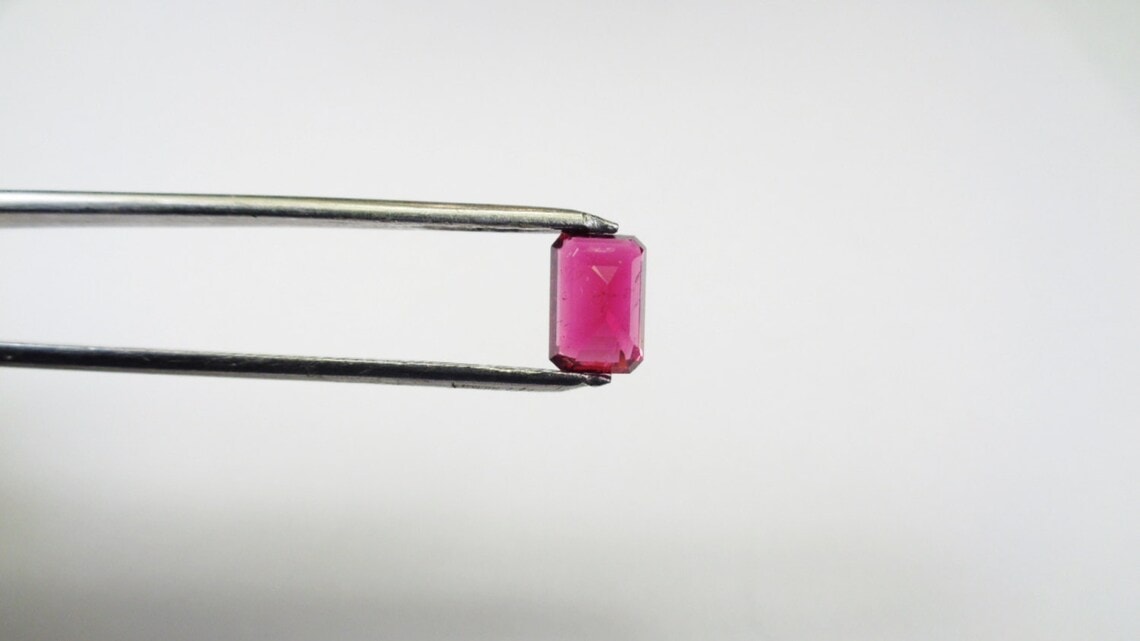 tweezers holding rubellite stone