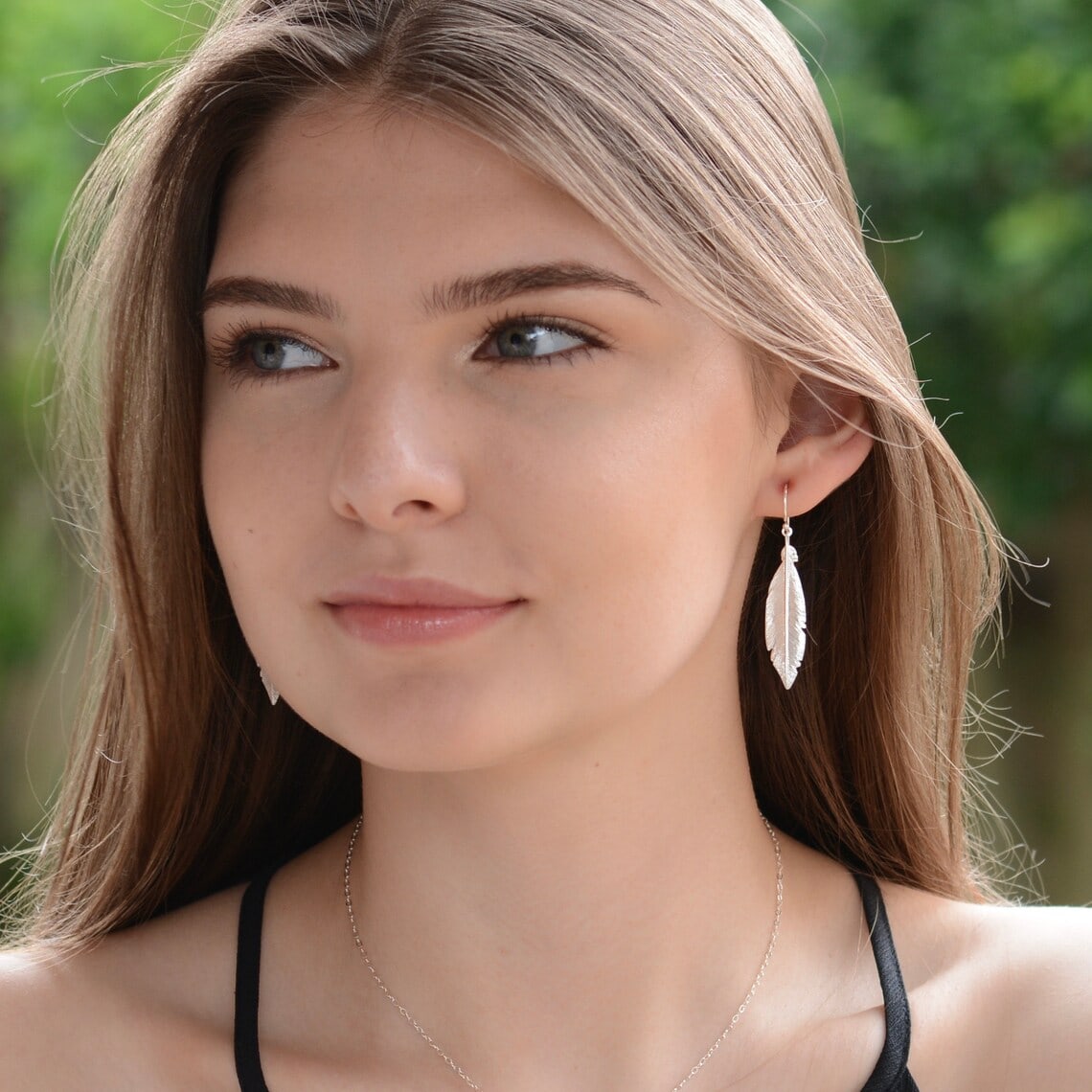 a woman wearing silver feather earrings