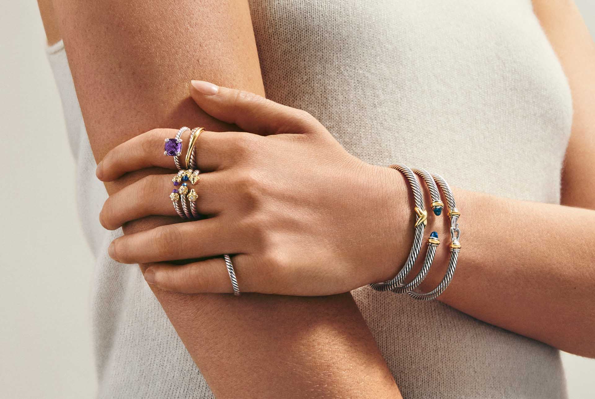 a woman wearing rope design bracelets and rings