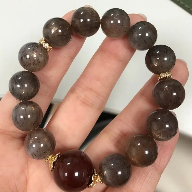 a hand holding a black sunstone beaded bracelet