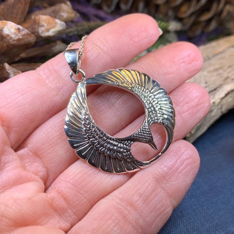 a hand holding eagle wings necklace