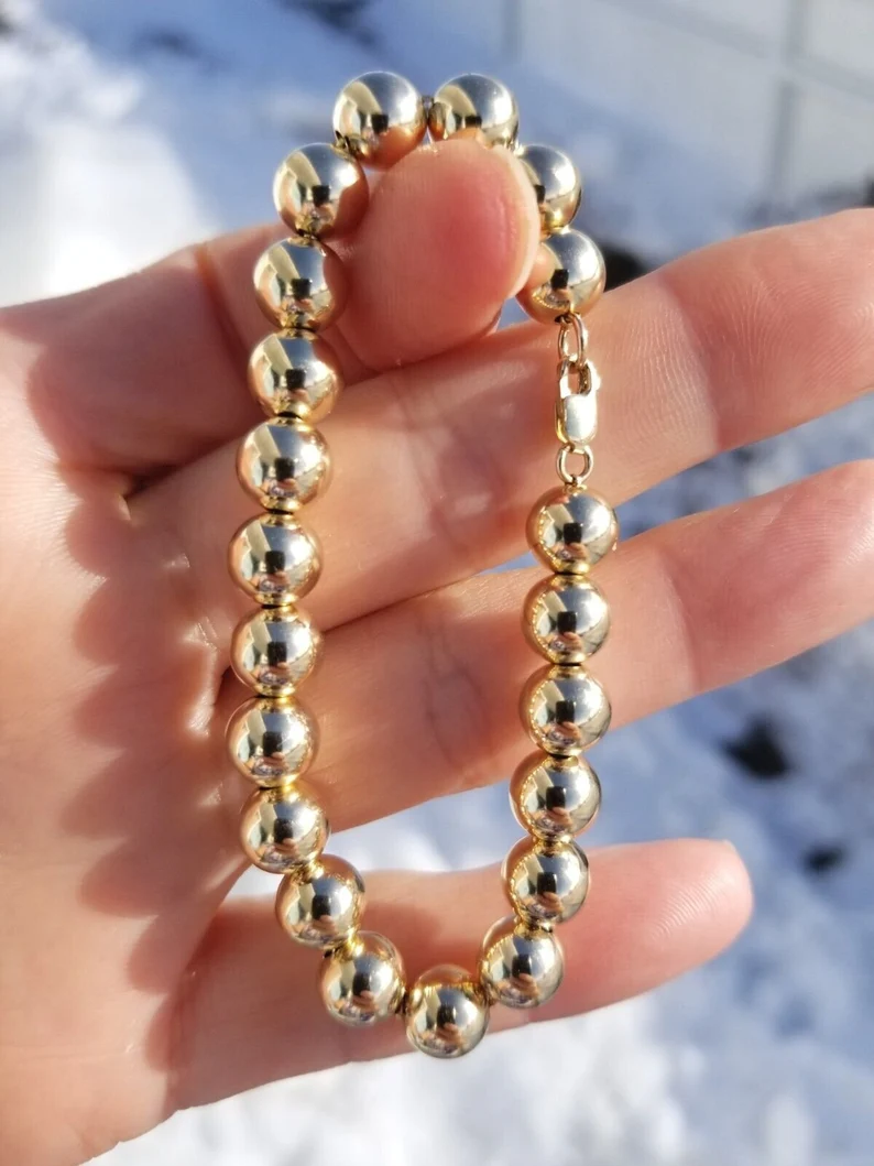 holding a gold ball chain men's bracelet
