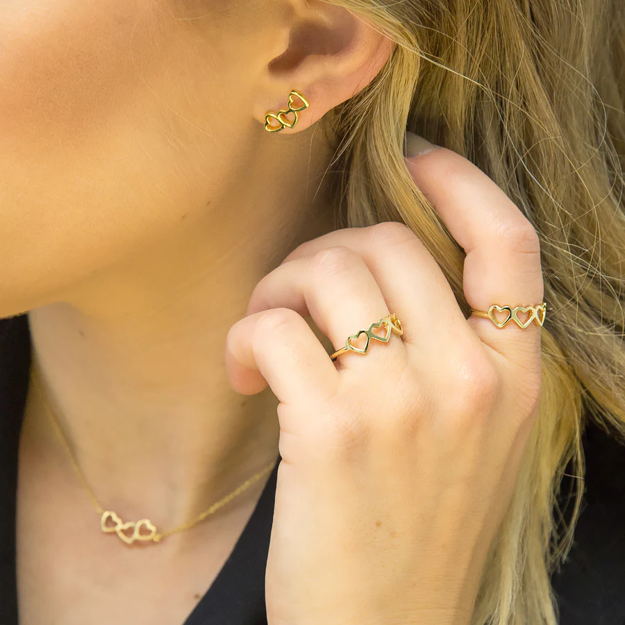 a woman wearing love heart design necklace, earrings and rings