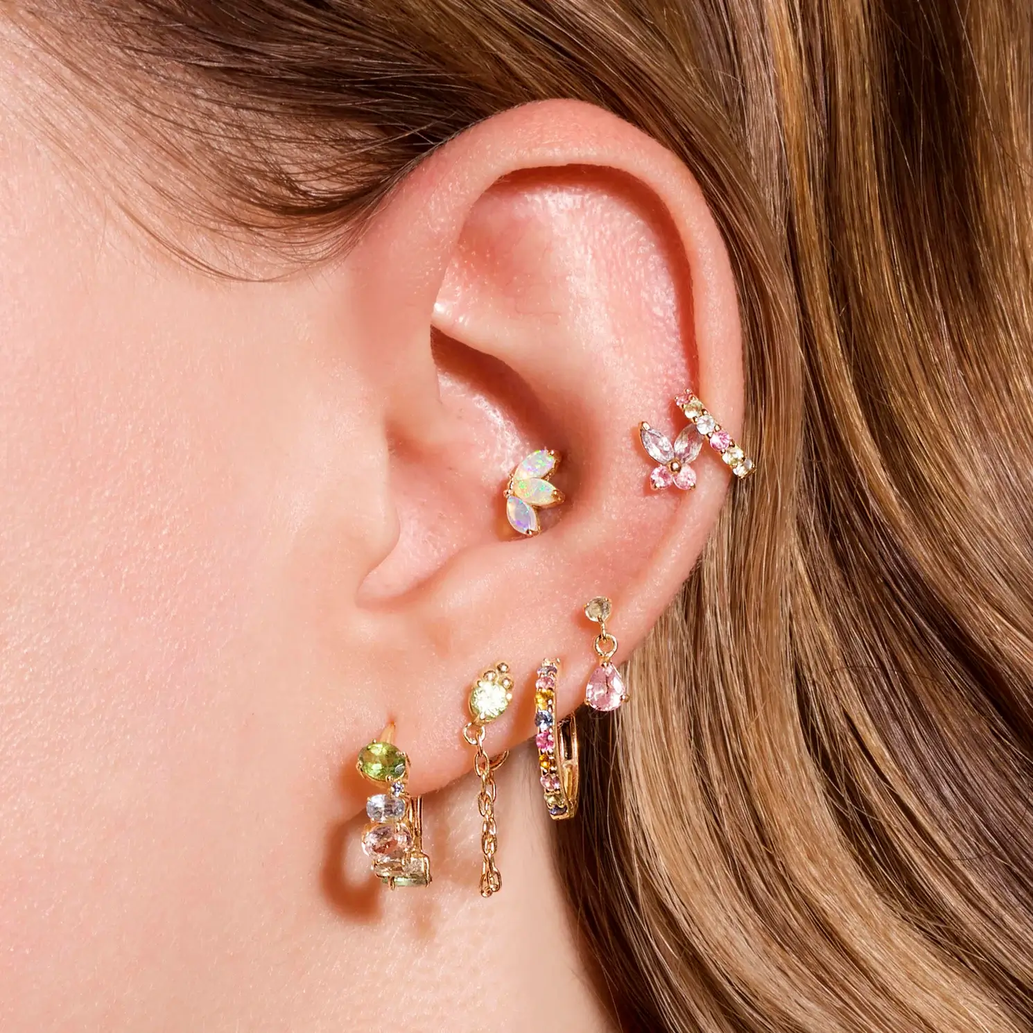 pastel butterfly studs on the woman's ear
